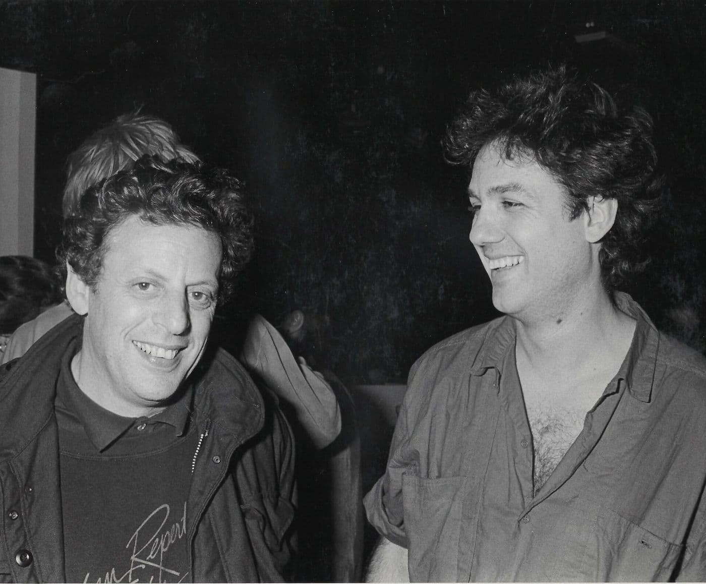 Zwart-witfoto van twee lachende mannen met krullend haar in de Mazzo: Philip Glass en Michiel van den Bergh
