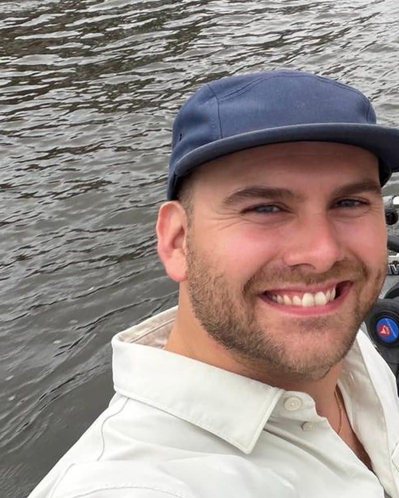 Niels van den Bergh, lachend met een pet op, in een bootje op de gracht
